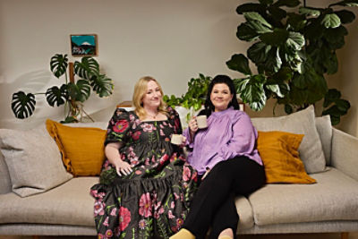 Rosie Waterland and Tanya Hennessy sitting on a sofa and drinking tea