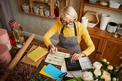 Female business owner using a calculator and writing in her notebook