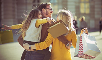 Young family hugging and carrying shopping bags