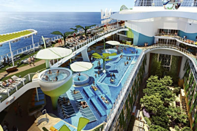  Aerial view of Royal Caribbean’s Icon of the Seas cruise ship, showing people in a swimming pool, spas, deck areas and central garden.
