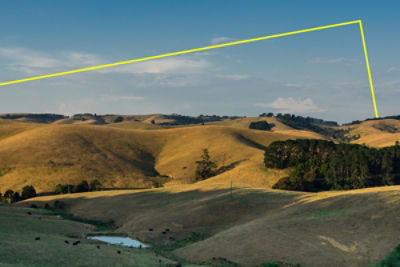 Regional landscape with rolling grass hills, a small lake, trees and a clear sky