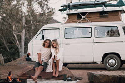 Couple on beach holding surfboard