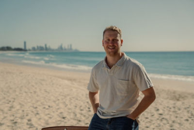 Man posing for a photo with beach as background