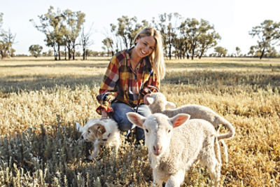 Woman with two sheep and a dog in a field.