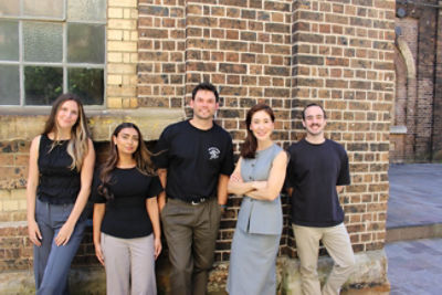 people standind against a brick wall smiling at the camera. 