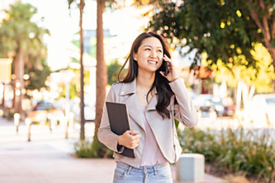 Woman speaks on the phone while holding a laptop