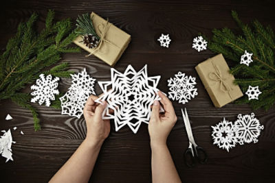 Paper snowflake decorations laid out on a table with gifts