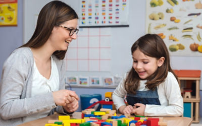 Childcare worker and child sitting at table