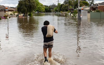 A local resident carries a sandbag through a flooded street in Shepparton. Credit: AAP Image/Diego Fedele