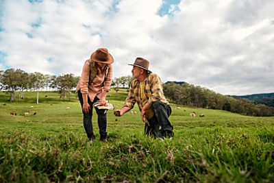 Farmer and mother passing an apple to her daughter in an orchard