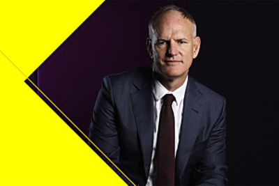 A professional portrait of Michael Miller in a suit against a dark background.