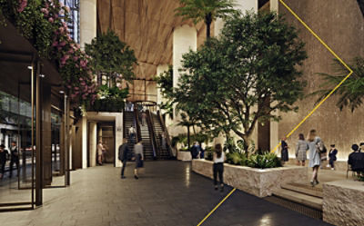 A spacious lobby with tall green trees and plants, warm lighting, and people walking or using the escalators.