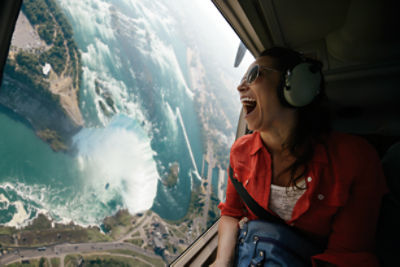 Woman in a helicopter looking down at a view through the window.