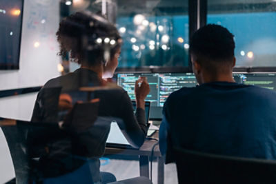 two people in an office looking at a computer screen