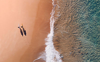 Aerial photo of two surfers on a beach, representing a relaxing in retirement