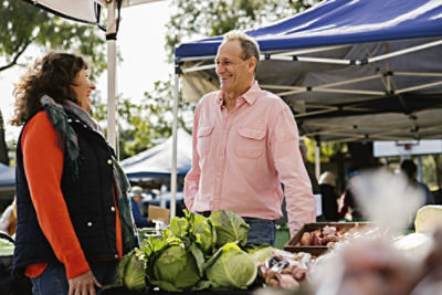 Richard Bennett standing with a woman at a produce stall at Willunga Farmer’s Market.