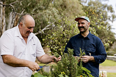 Tony Mitolo standing with another man who is cutting herbs.
