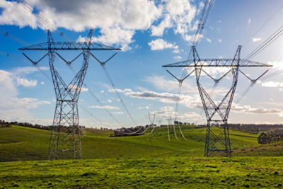 View of open green grass fields with small hills, with power lines off in the distance