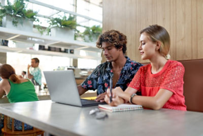 A young couple looking at a laptop in a cafe. Credit: Adobe Stock