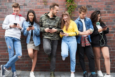 A group looking at their phones. Credit: Adobe Stock