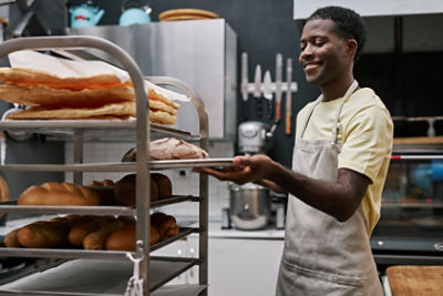 Baker putting loaves of bread on shelf
