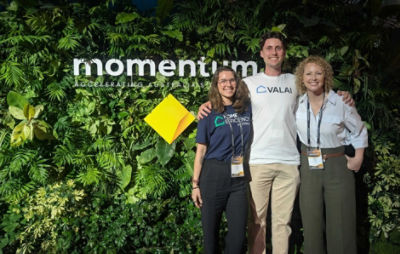 Two women and a man smiling for photo in front of CommBank and Momentum logo's