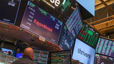 A screen displays stock information for ExxonMobil, an oil and gas company, as traders work on the floor of the New York Stock Exchange in New York.
