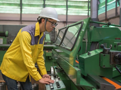 A factory worker in China operates a laser lathe: Credit Adobe Stock
