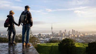 Couple standing on Mt Eden summit and watching sunrise over Auckland city.  Credit: Adobe Stock