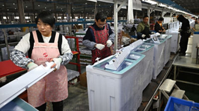 Workers install washing machines at a factory making washing machines for export, in Suqian in east China's Jiangsu province on Oct. 20, 2025. (Chinatopix Via AP)
