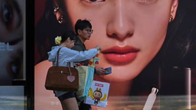 Shoppers with their purchased goods walk by a luxury cosmetic store at an outdoor shopping mall, in Beijing, Monday, April 14, 2025. (AP Photo/Andy Wong)