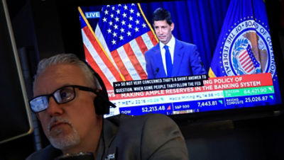 A trader works as a screen broadcasts a press conference by US. Federal Reserve Chair Kevin Warsh following the Fed rate announcement, on the floor of the New York Stock Exchange (NYSE) in New York City, U.S., July 29, 2026. REUTERS/Brendan McDermid