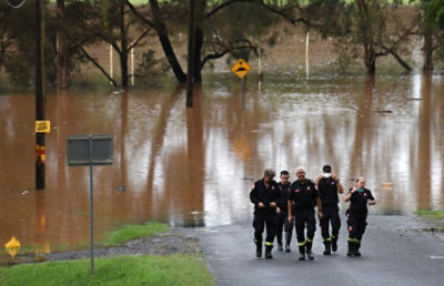 A group of firefighters are seen near flood waters in Lismore, NSW, Tuesday, March 29, 2022. Residents in parts of north and south Lismore and low-lying parts of Kyogle in northern NSW are evacuating from their homes as life-threatening flooding hits the region again. (AAP Image/Darren England) NO ARCHIVING
