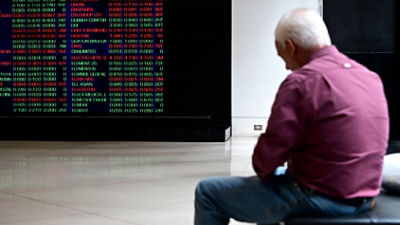 An older investor sits in front of the ASX board