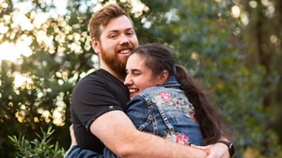 Happy young people hug with man looking at the camera. Picture: Adobe