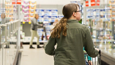 A woman pushing shopping trolley down cold aisle in supermarket. Photo: Clare Seibel-Barnes/Austockphoto