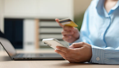 A person with a credit card, phone and laptop