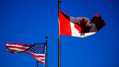 The flags of Canada and the United States fly outside a hotel in downtown Ottawa, on Saturday, Feb. 1, 2025. (Justin Tang/The Canadian Press via AP)