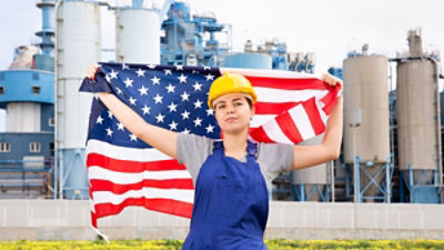 A young blue-collar worker holds an American flag. Credit: JackF/Adobe 
