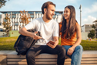 Happy confident couple with a mobile phone outdoor in city.