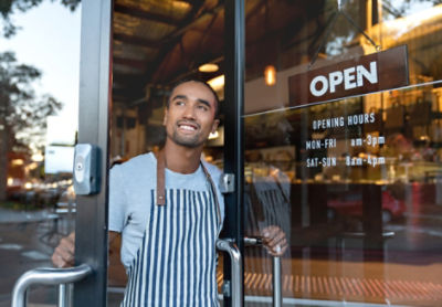 Small Business owner opening cafe door with open sign 