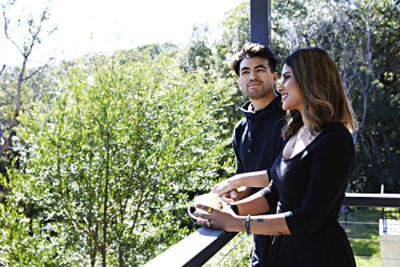 Quincy Lim and Krish Waje standing on their balcony looking out to trees.